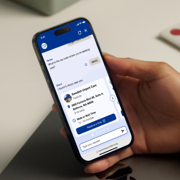 A hand holding a phone showing the Grace assistant returning a nearby urgent care clinic with its address and wait time.